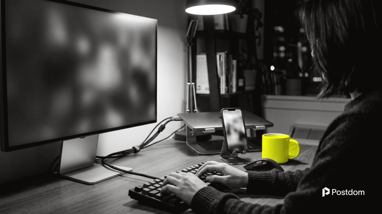 Instagram Reels API: a developer types at a keyboard at night beside a monitor, a phone on a stand and a yellow mug