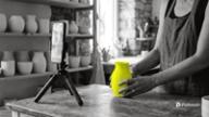 How to schedule TikTok posts: a ceramics shop owner places a yellow vase in front of a phone recording on a small tripod