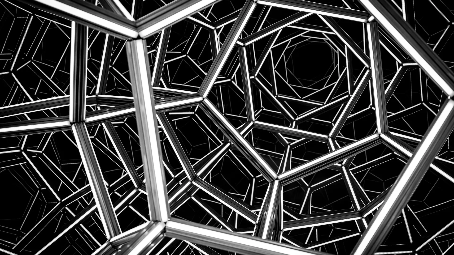 Illuminated pentagonal frames reflected endlessly in a mirrored chamber, black and white