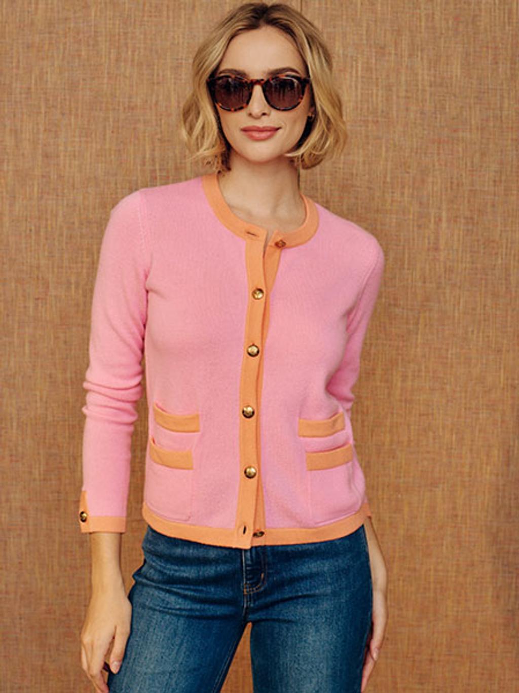 Model in pink cardigan and blue denim wearing sunglasses