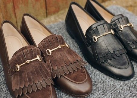 laydown of womens penny loafers in brown and black leather with tassles and bamboo buckle