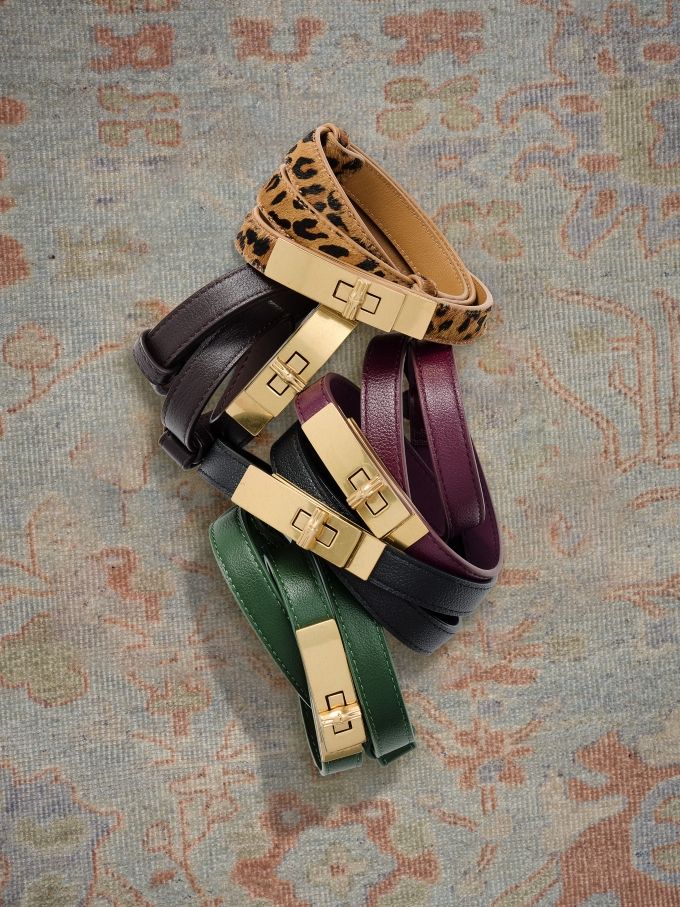 group of womens skinny belts in various colors on geo pattern carpet