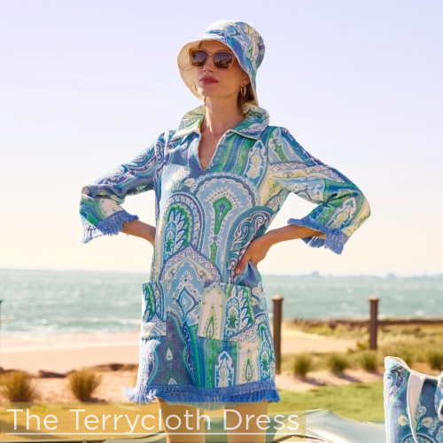 woman standing in backseat of car with the ocean behind her wearing blue multicolor paisley terrycloth coverup dress and matching bucket hat