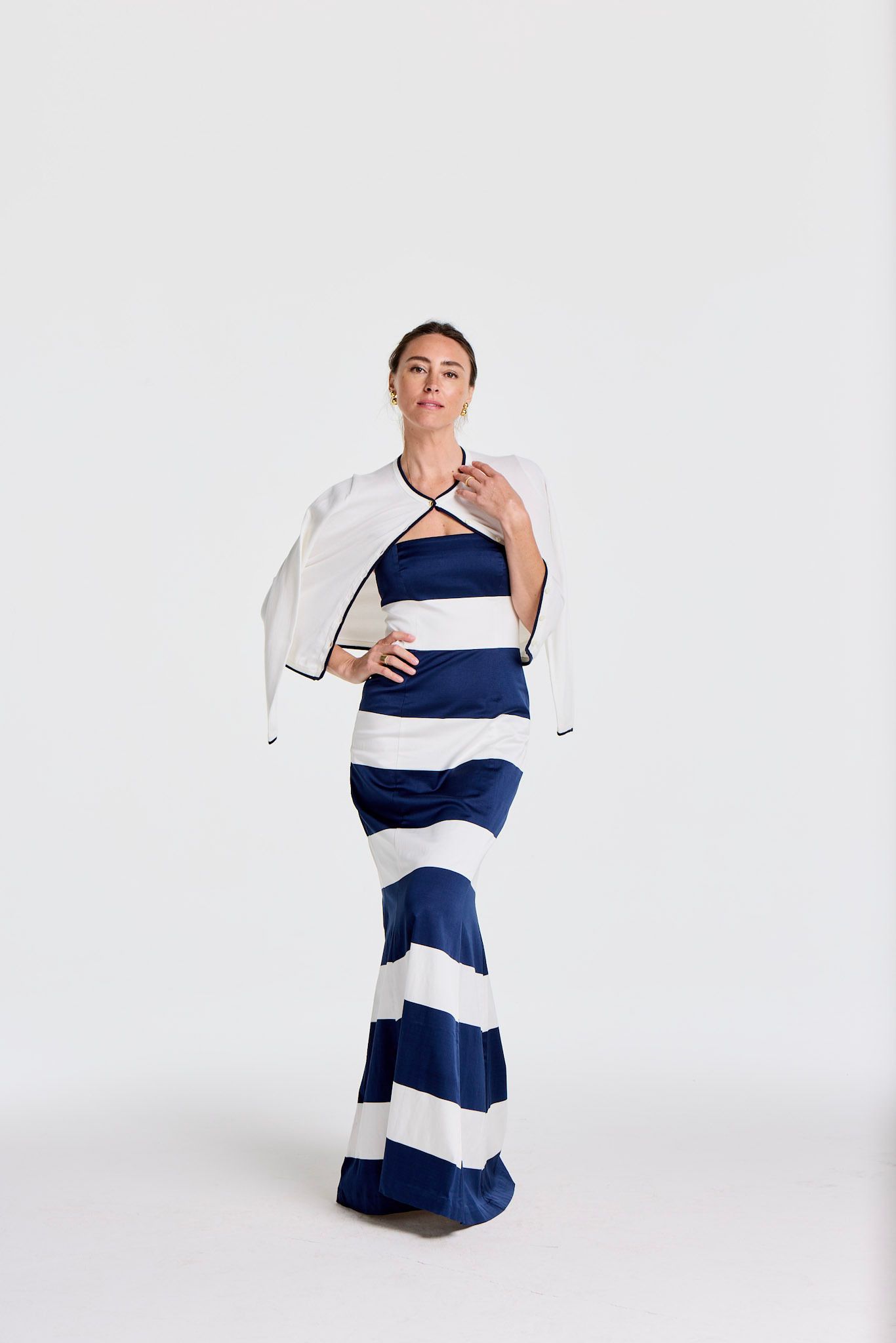 A woman in a navy blue and white striped strapless gown with a white bolero jacket.