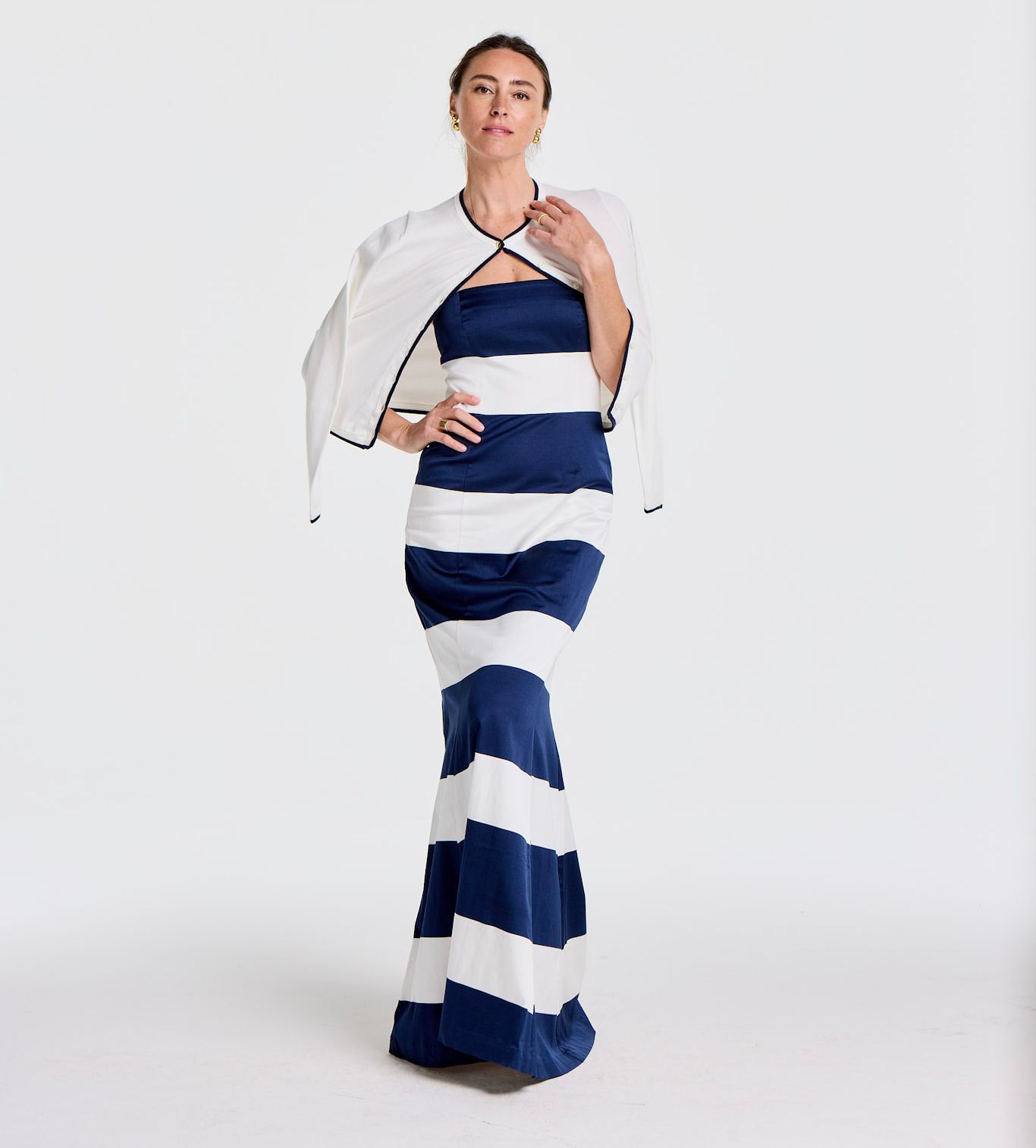 A woman in a navy blue and white striped strapless gown with a white bolero jacket.