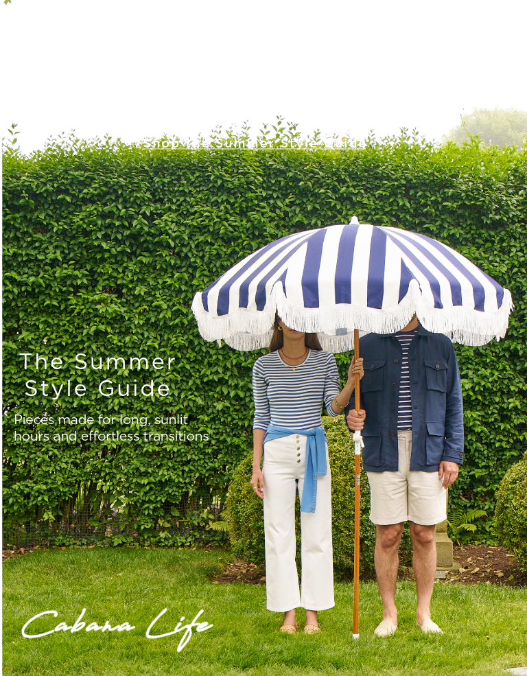 man and woman standing outside in navy and white outfits holding a blue and white stripe umbrella