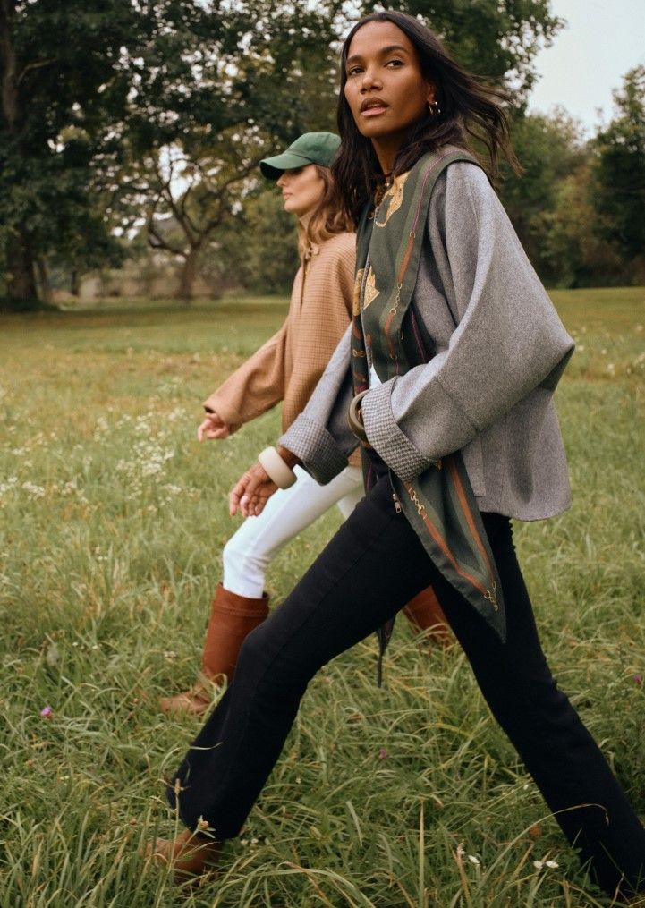 two women walking in field wearing reversible capes
