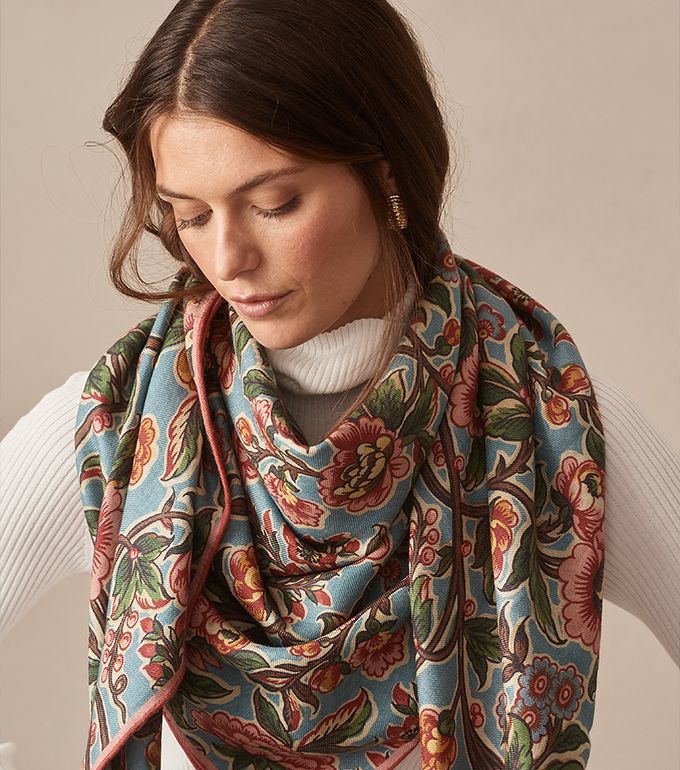 cropped in image of woman wearing white thin rib turtleneck with oversized multicolor floral scarf wrapped around her neck