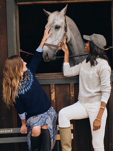 Two models posing and petting white horse