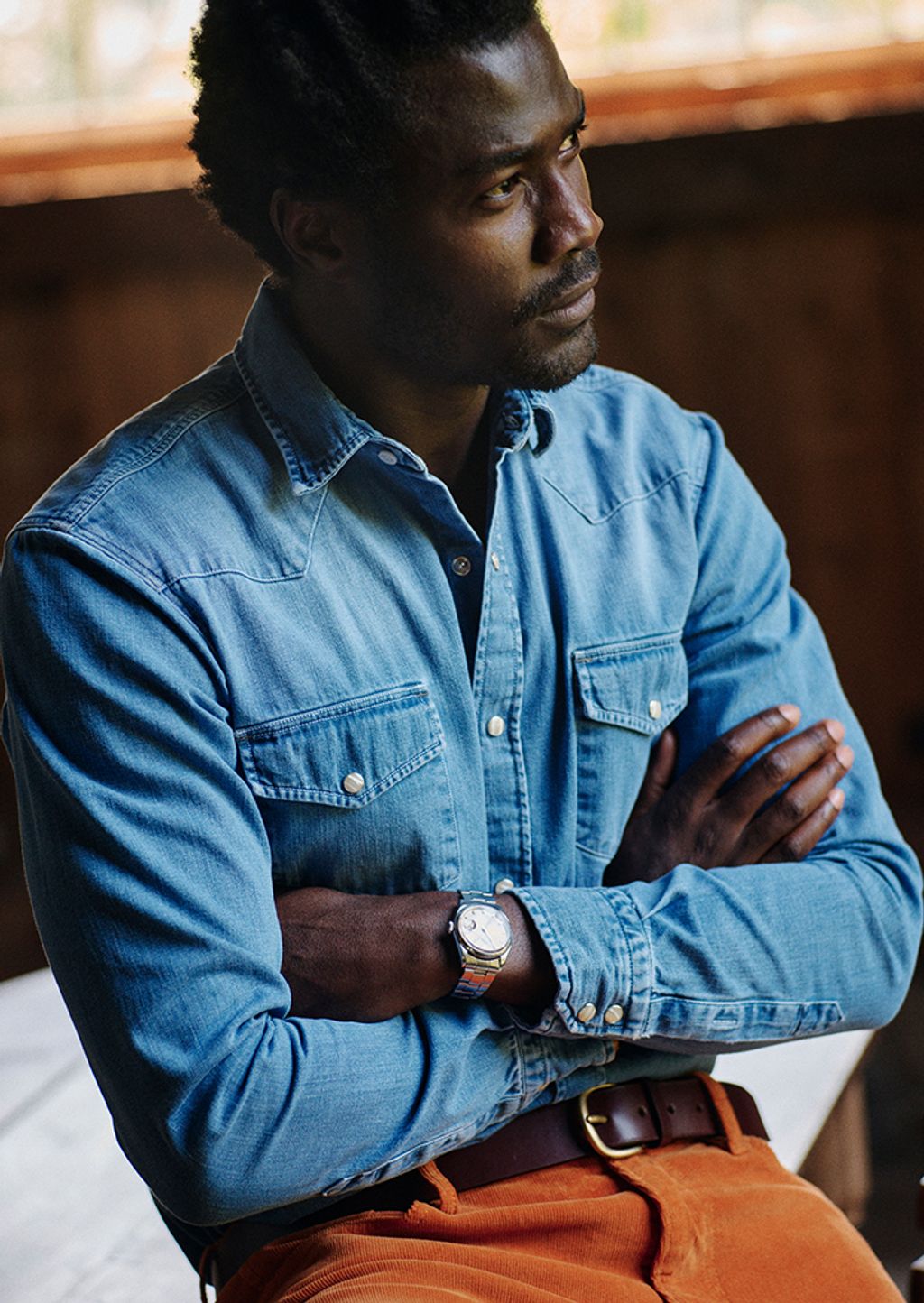 Male model wearing a denim shirt and orange corduroy pants,