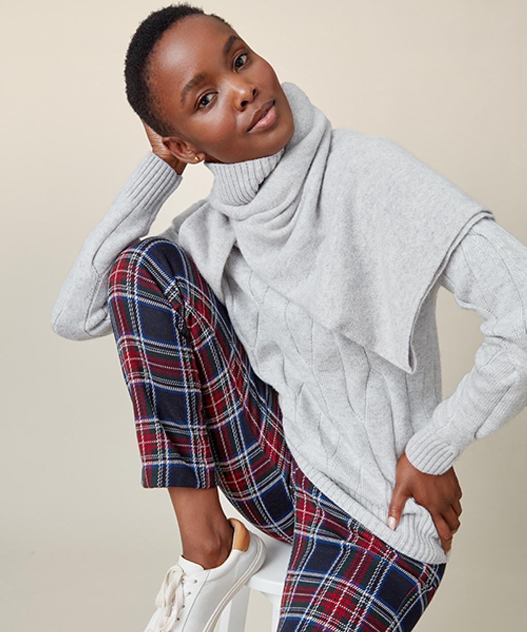Model wearing tartan pants, cashmere turtleneck sweater, and leather sneakers.