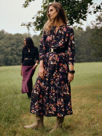 woman standing outside on lawn in black floral printed long dress