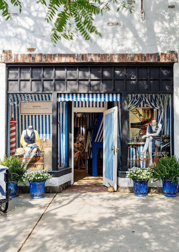 image from the street of exterior of womens lifestyle boutique with blue and white striped cabana motif and two mannequins in swimwear in the windows