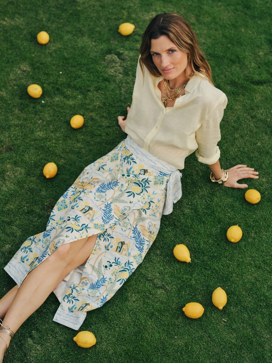 woman on grass with lemons wearing printed skirt