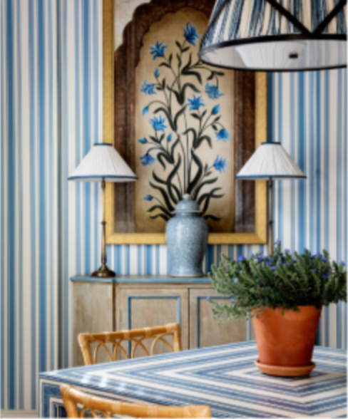 Blue and white striped room featuring an arched artwork with blue flowers, two lamps, and a patterned table with a potted plant.