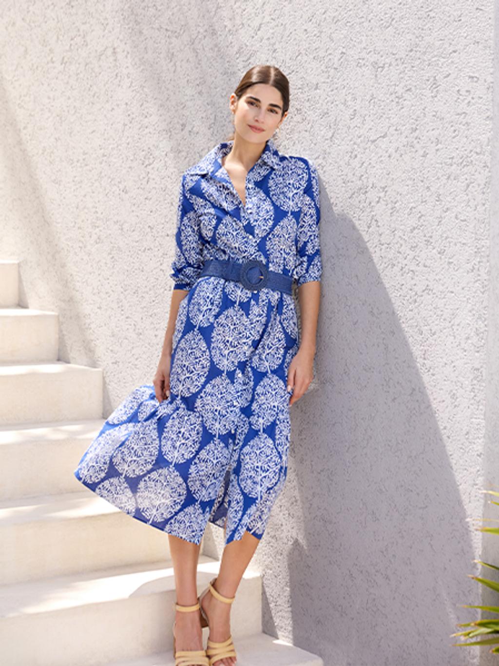 Woman in blue floral dress, blue belt, and tan sandals