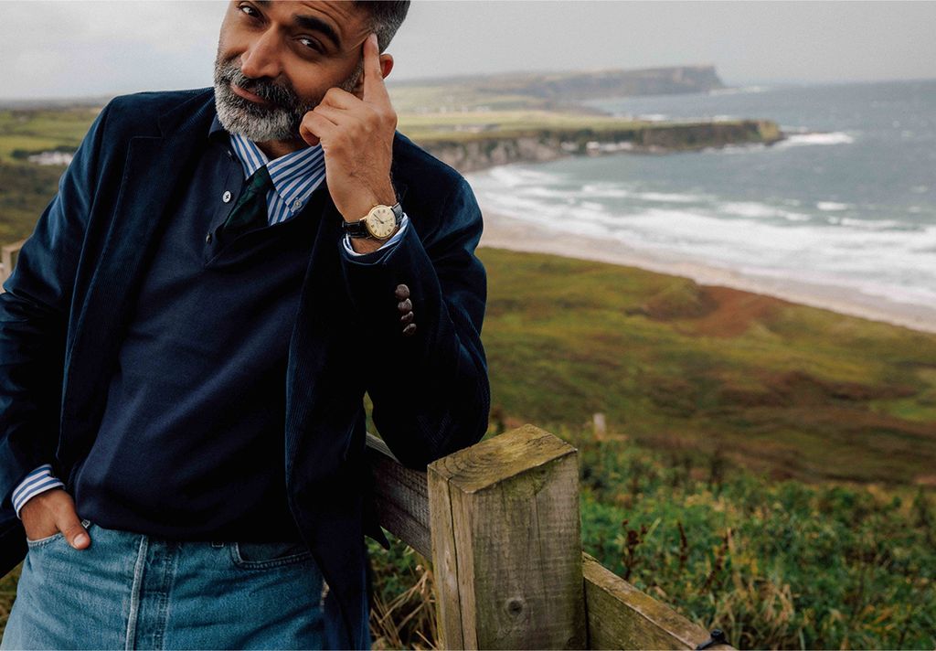 man leaning on fence in navy corduroy blazer