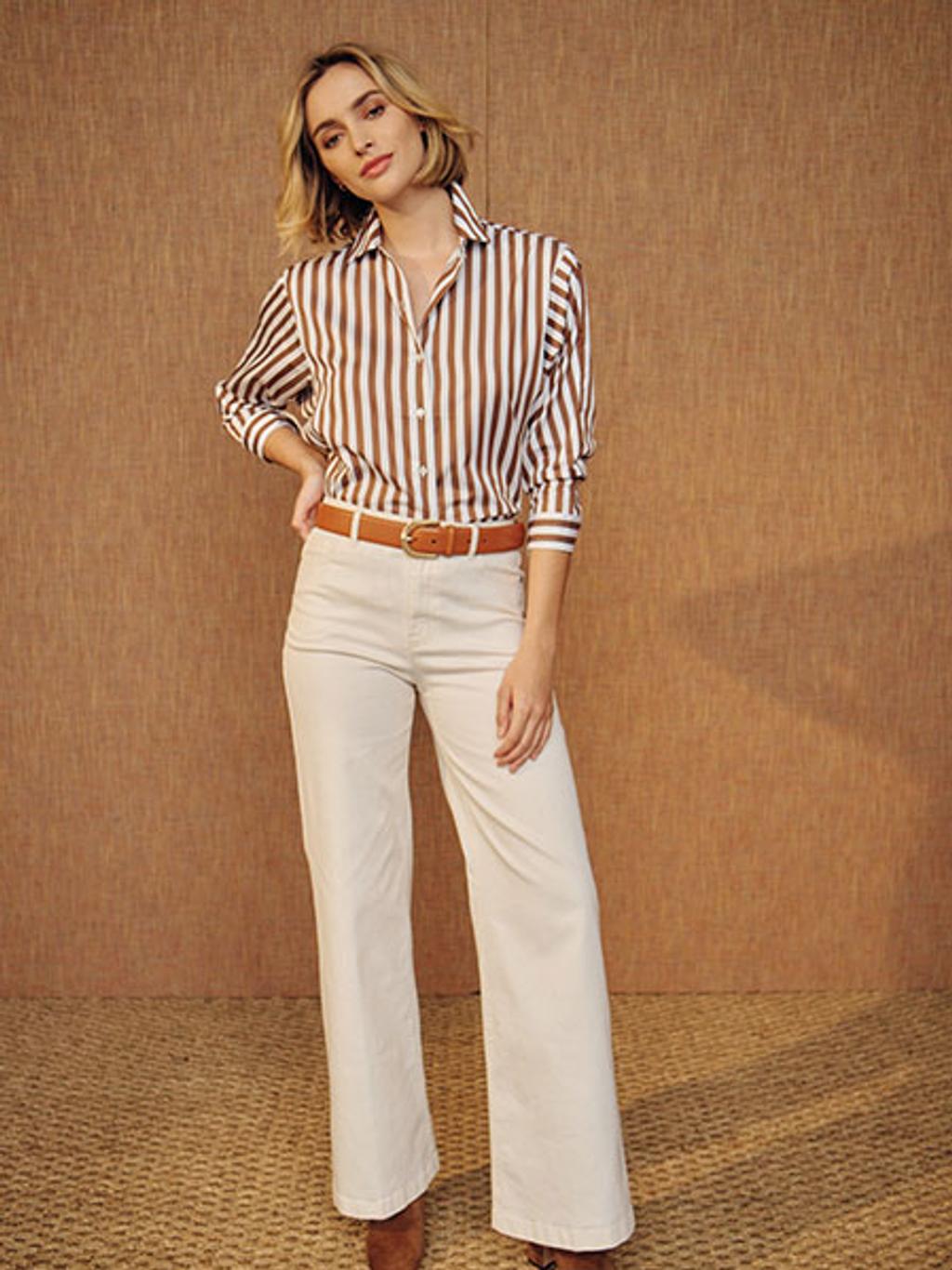Model in brown striped shirt, ivory jeans, and brown boots Model in brown striped shirt, ivory jeans, and brown boots