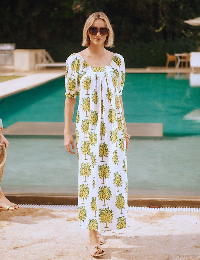 woman standing poolside in white flowy long dress with lemon pattern