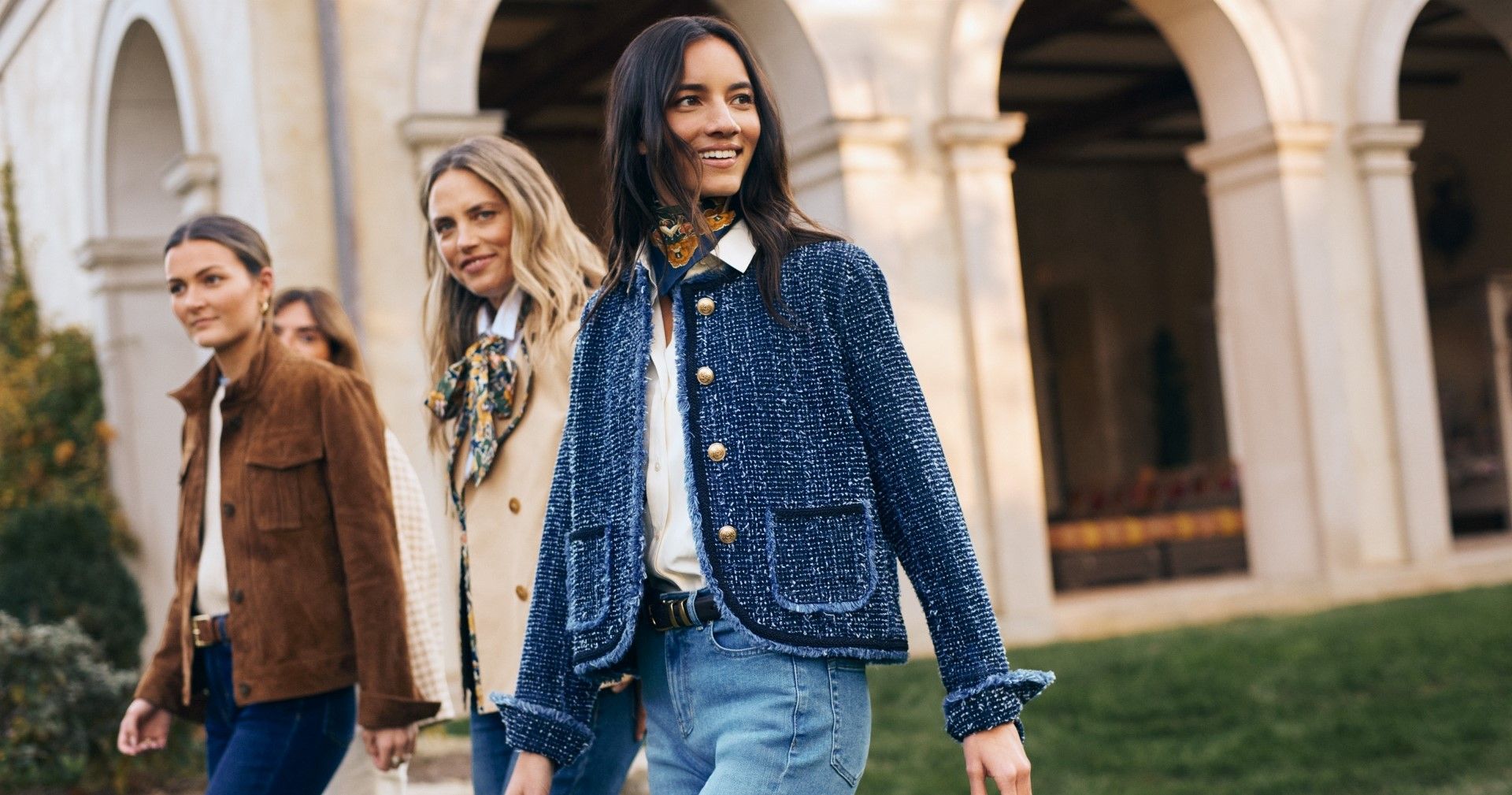 group of women walking outside, the one in the front wearing a navy tweed knit jacket with denim jeans