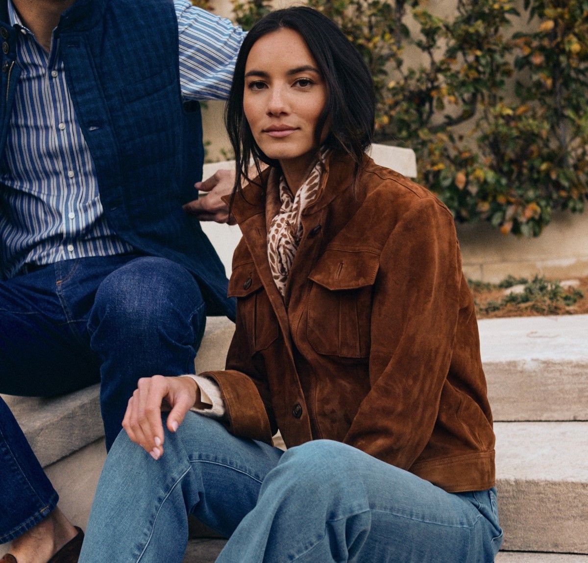 woman seated outside in brown suede jacket