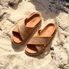 pair of tan criss cross leather and raffia sandals on beach