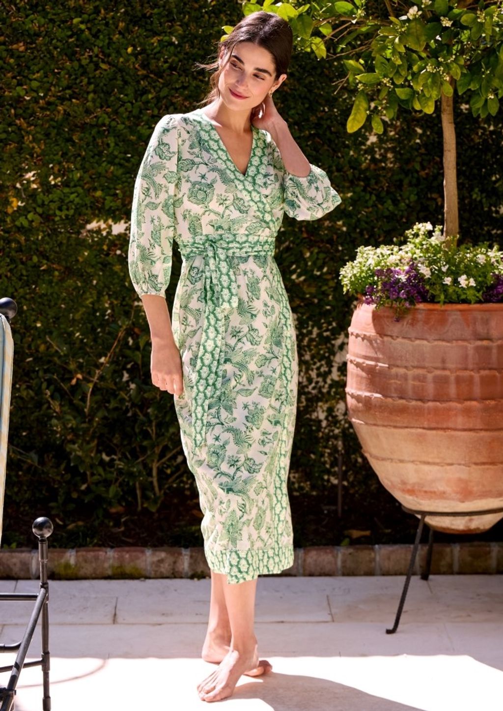 woman standing poolside in a green and white geo pattern wrap dress