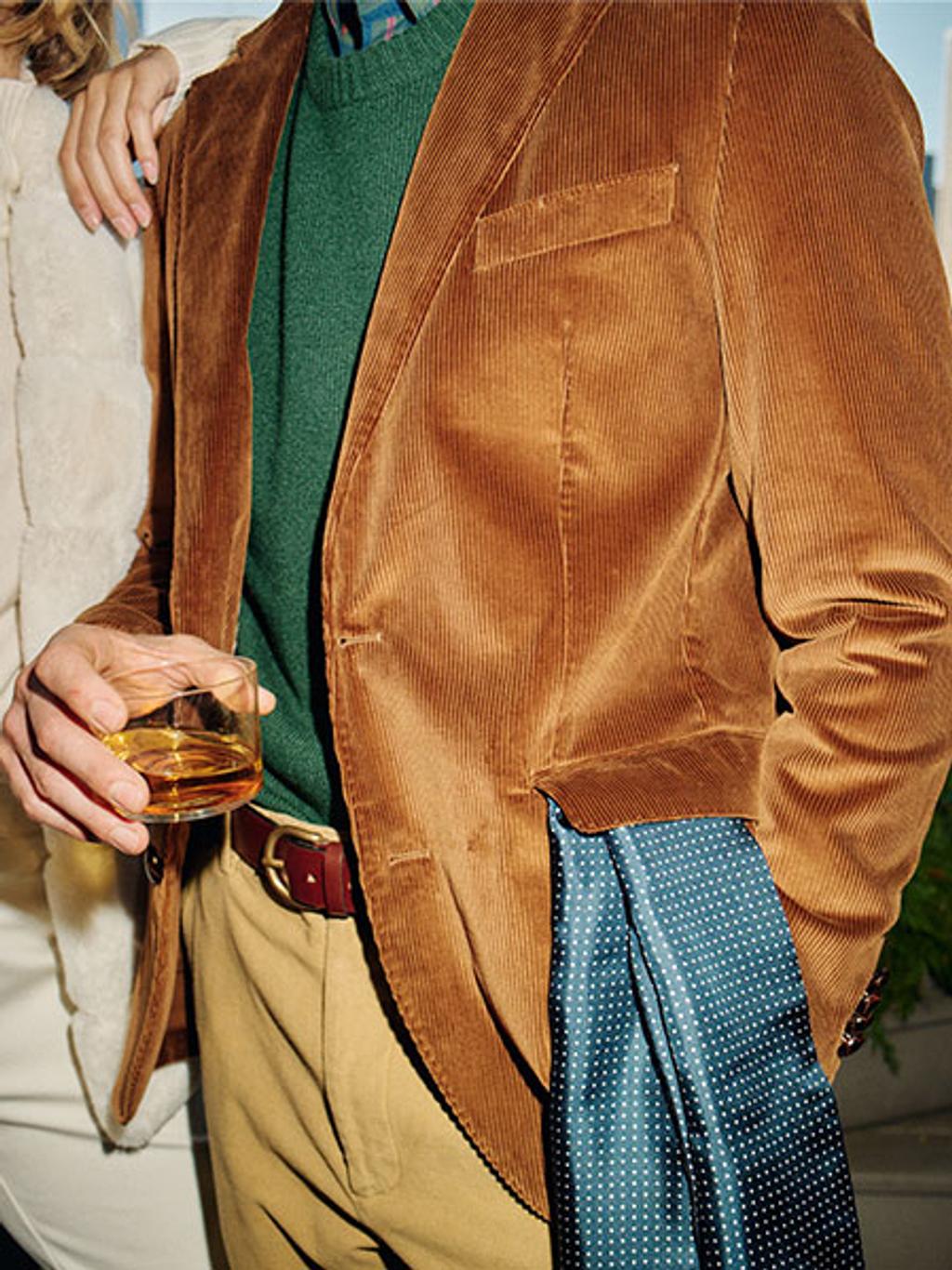 Model wearing a brown jacket and green crewneck sweater.