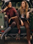 two women seated on back of a truck wearing quilted jackets and dark brown pants with boots