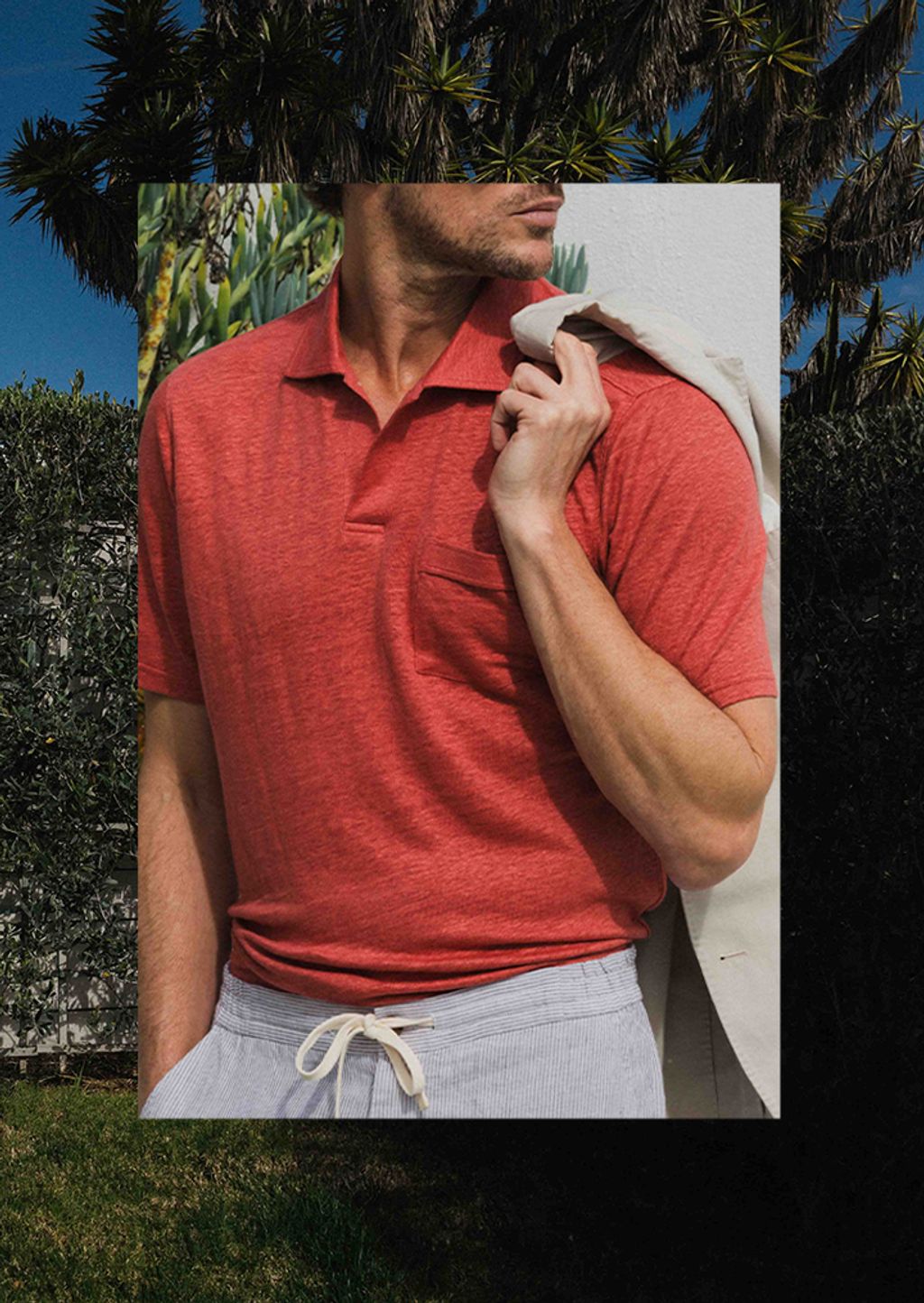 Man in red linen polo holding navy blazer over shoulder