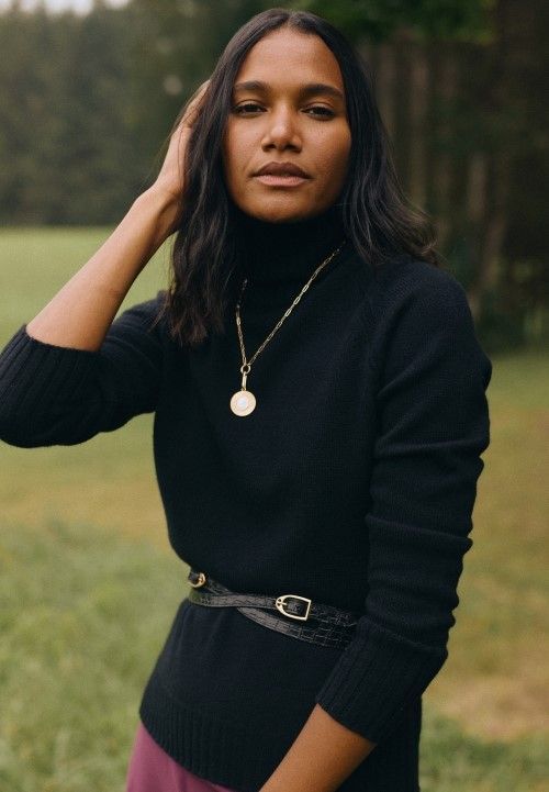 close up of woman standing outside in a field wearing black cashmere turtleneck sweater