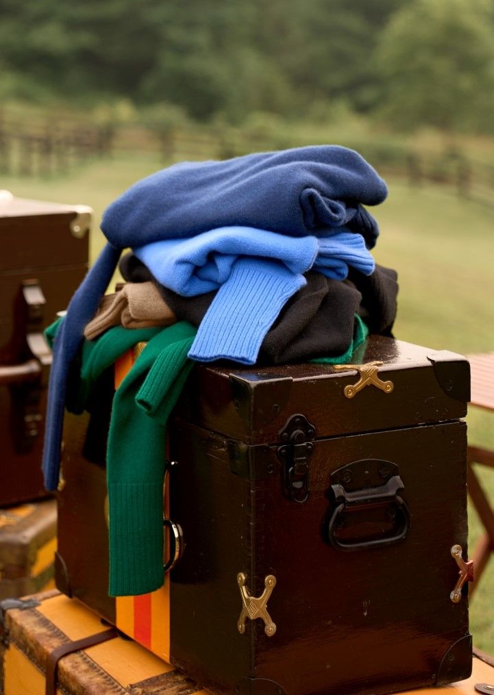 stack of womens cashmere turtleneck sweaters on top of steamer trunk
