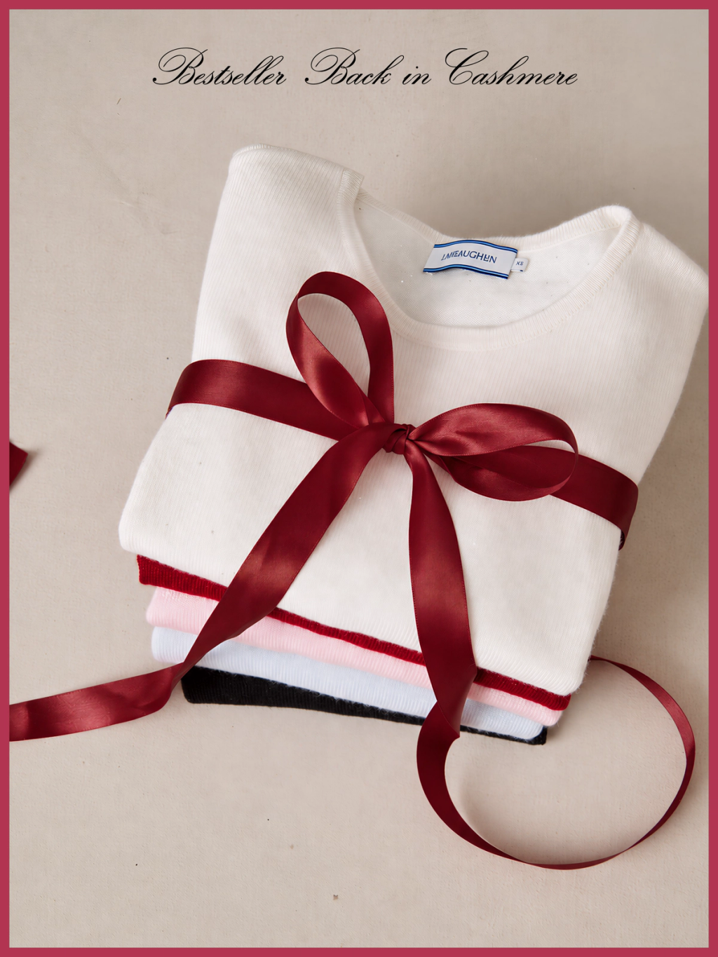 Stack of folded cashmere sweaters in various colors tied with a red ribbon and bow. Text reads: "Bestseller Back in Cashmere".