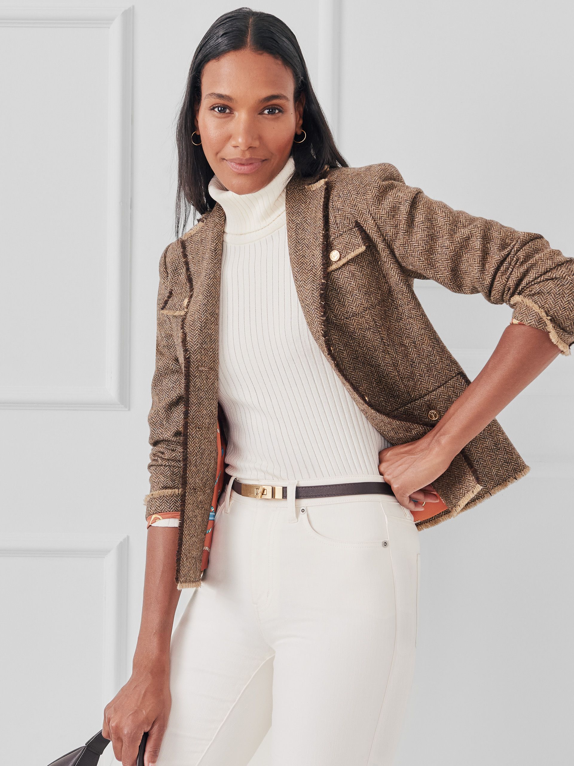 Model wearing white turtleneck, herringbone pattern, and white pants. 