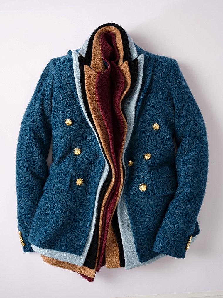 A teal double-breasted blazer with golden buttons showing layered fabrics in light blue, black, tan, and burgundy.