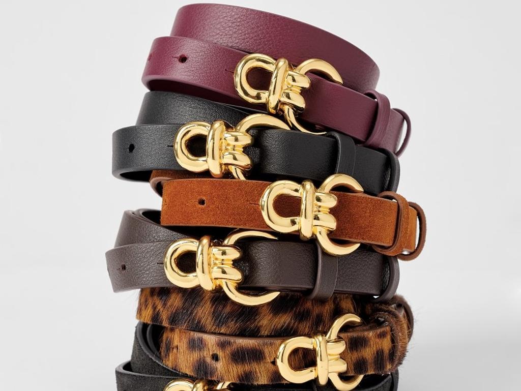 Stack of belts in various colors and textures with gold Gancini buckles.