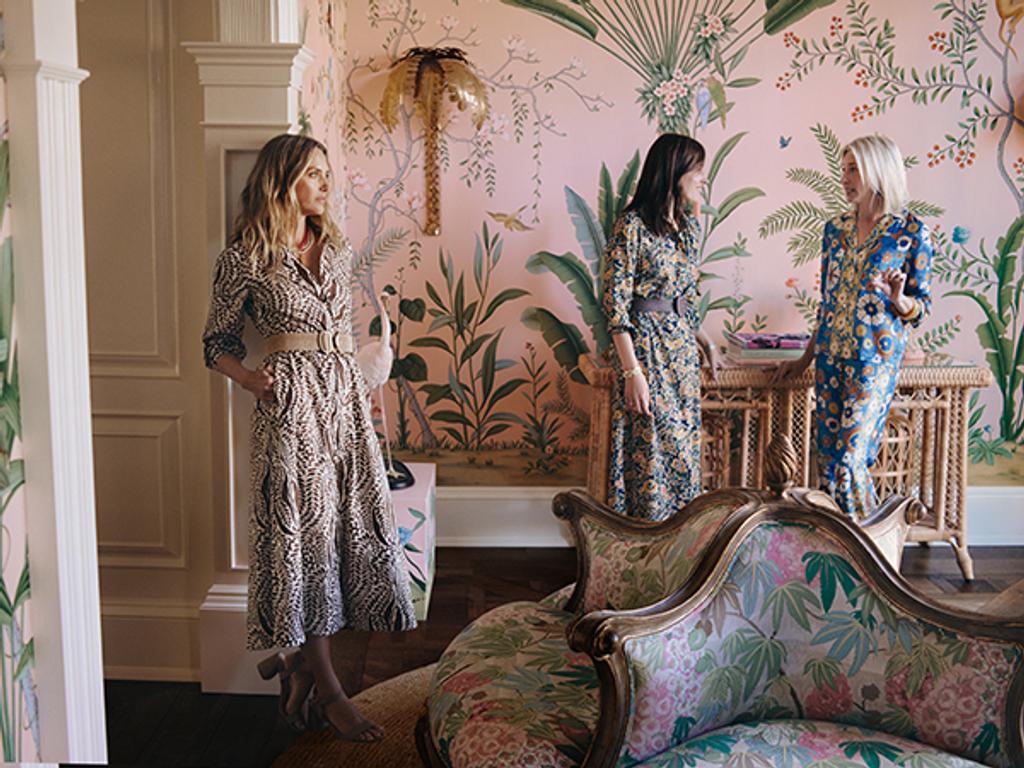 Three female models in various outfits, interior of a home