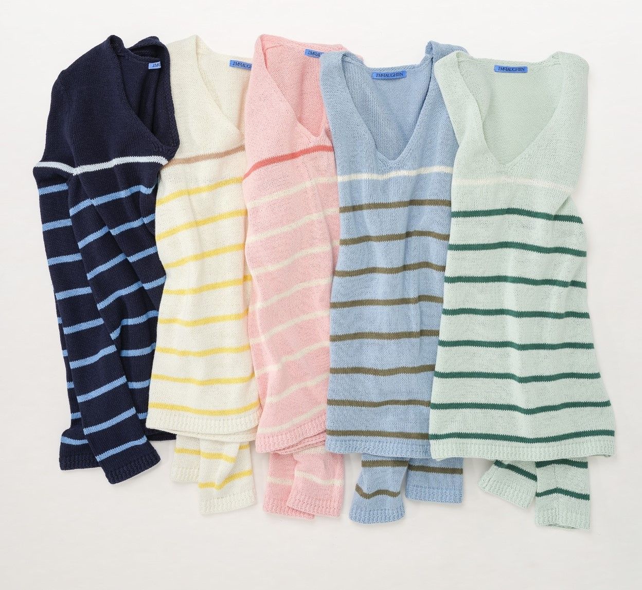 Five striped knit v-neck sweaters in different color combinations, laid flat.