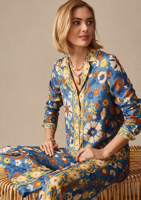 woman seated, wearing multicolor floral printed silk pant and matching button down blouse