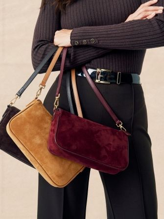 close up image of woman holding suede zip top shoulder bag