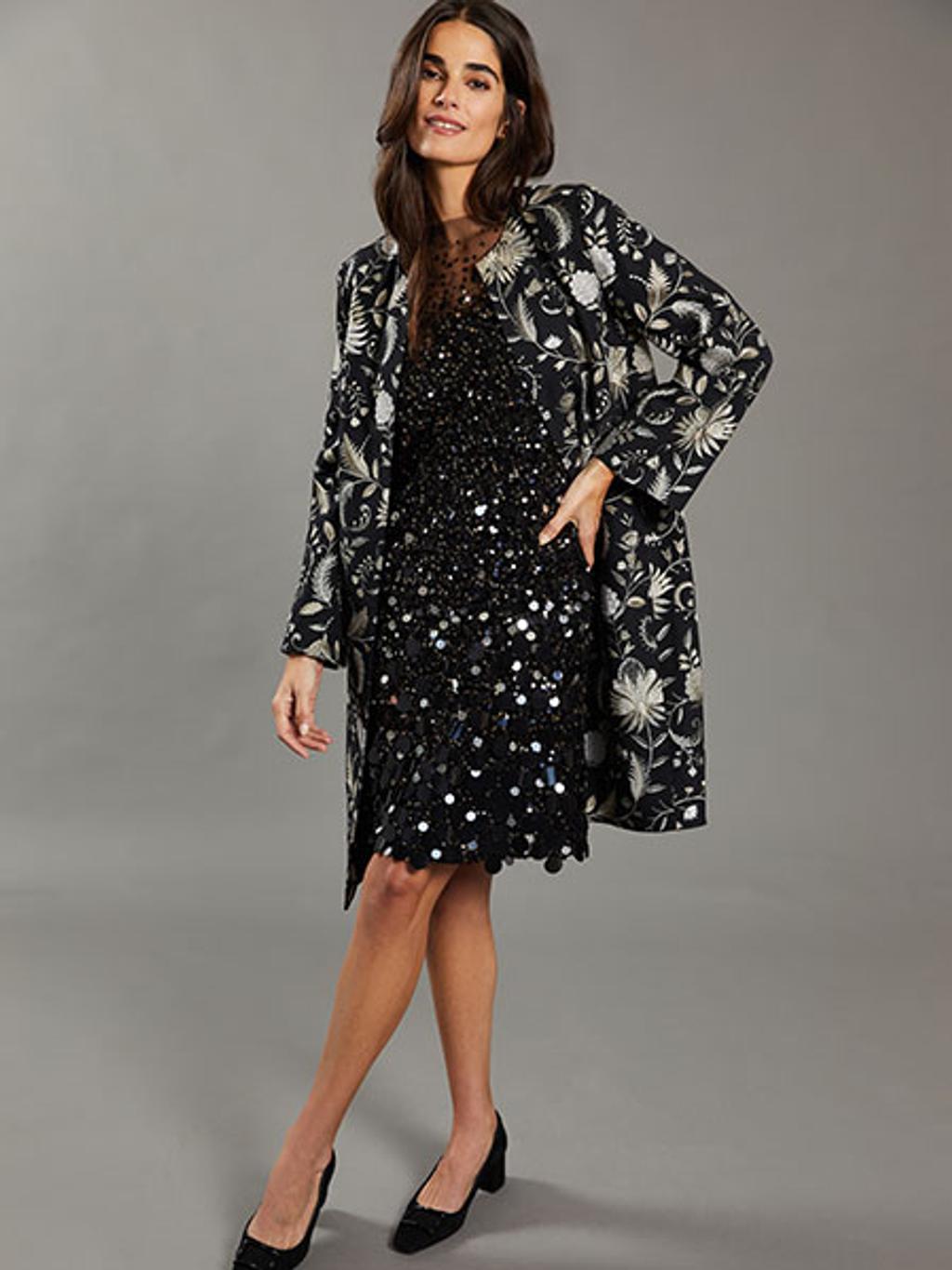 Model wearing embroidered coat and black sequined dress