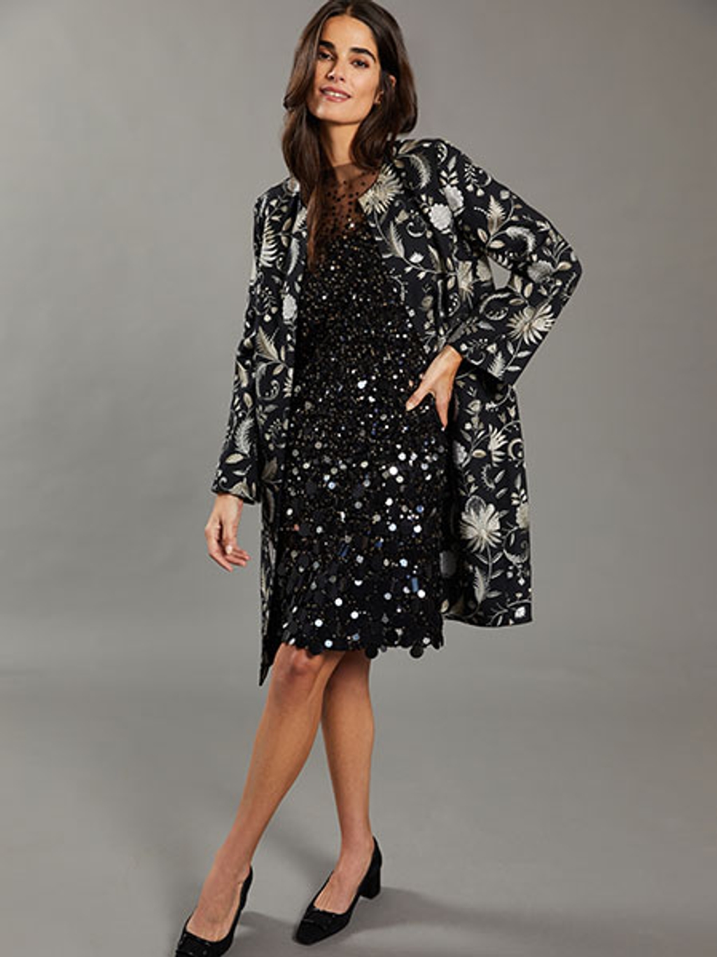 Model wearing embroidered coat and black sequined dress Model wearing embroidered coat and black sequined dress