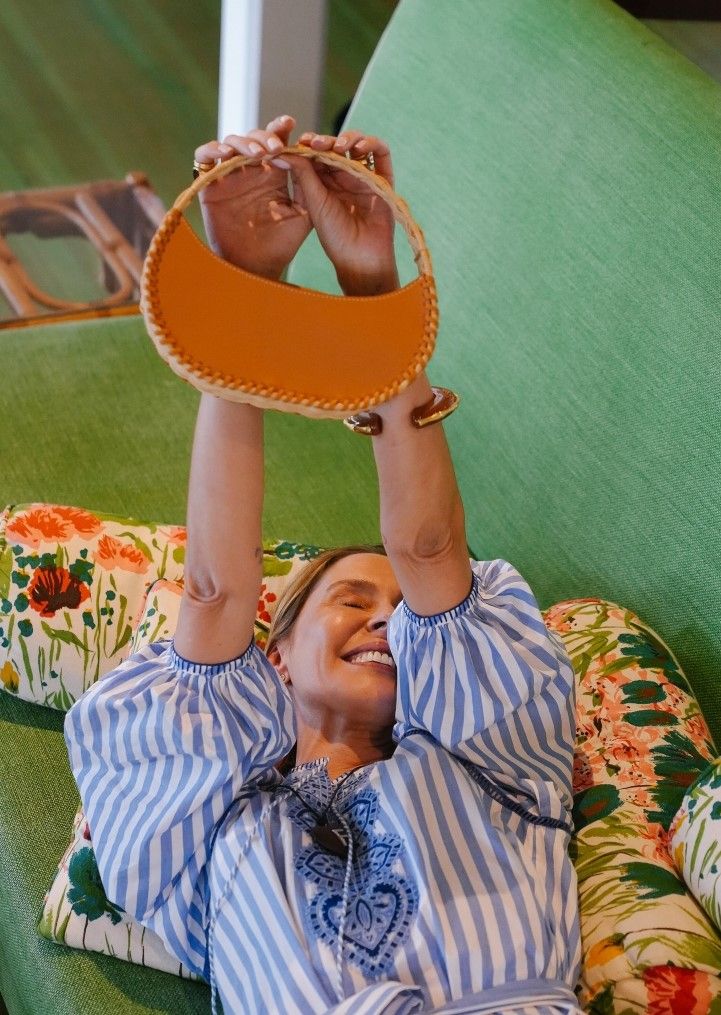 lady on couch holding up a handbag