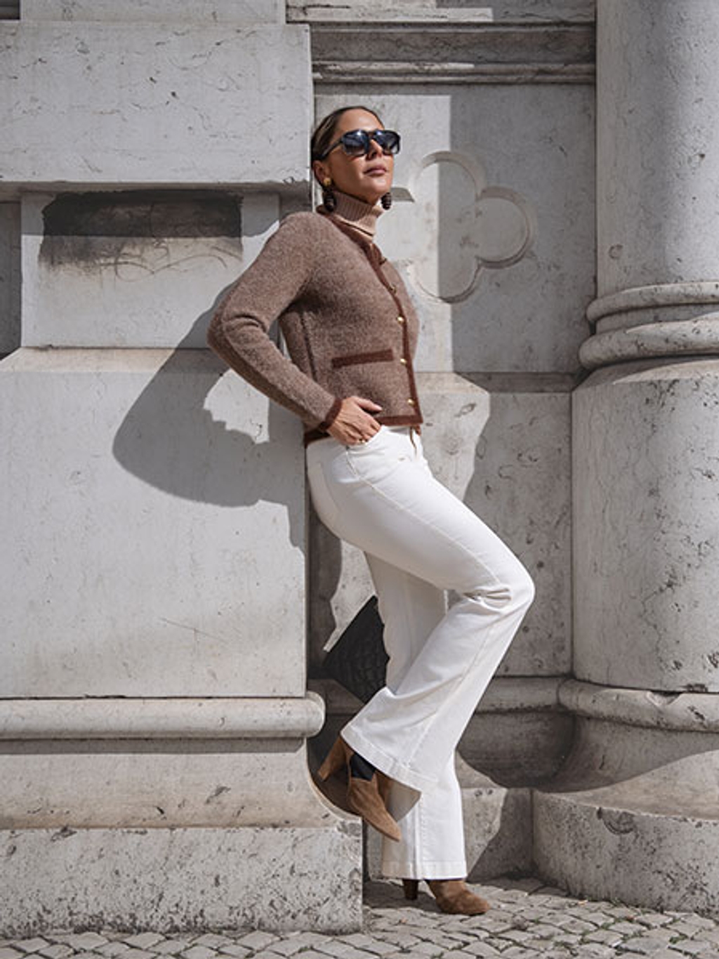 Filipa in brown cardigan, camel turtleneck, white jeans, and brown boots