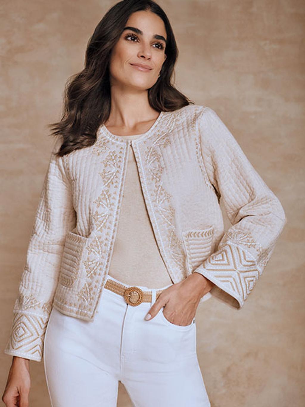 Model wearing embroidered jacket and white jeans.