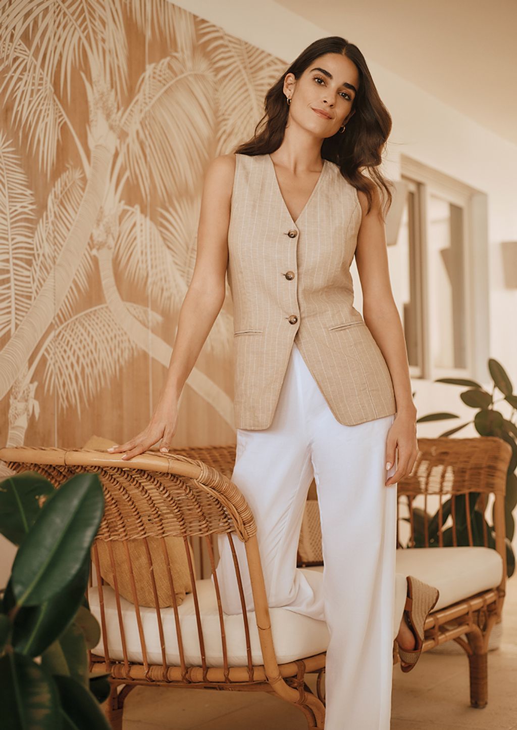 Woman seated on a chair wearing a matching shirt and pant in a white and blue chinoiserie print.