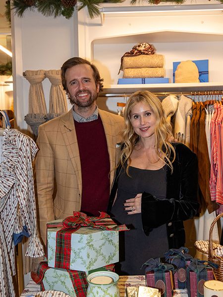 Man and women posed together for a photo in front of holiday presents.