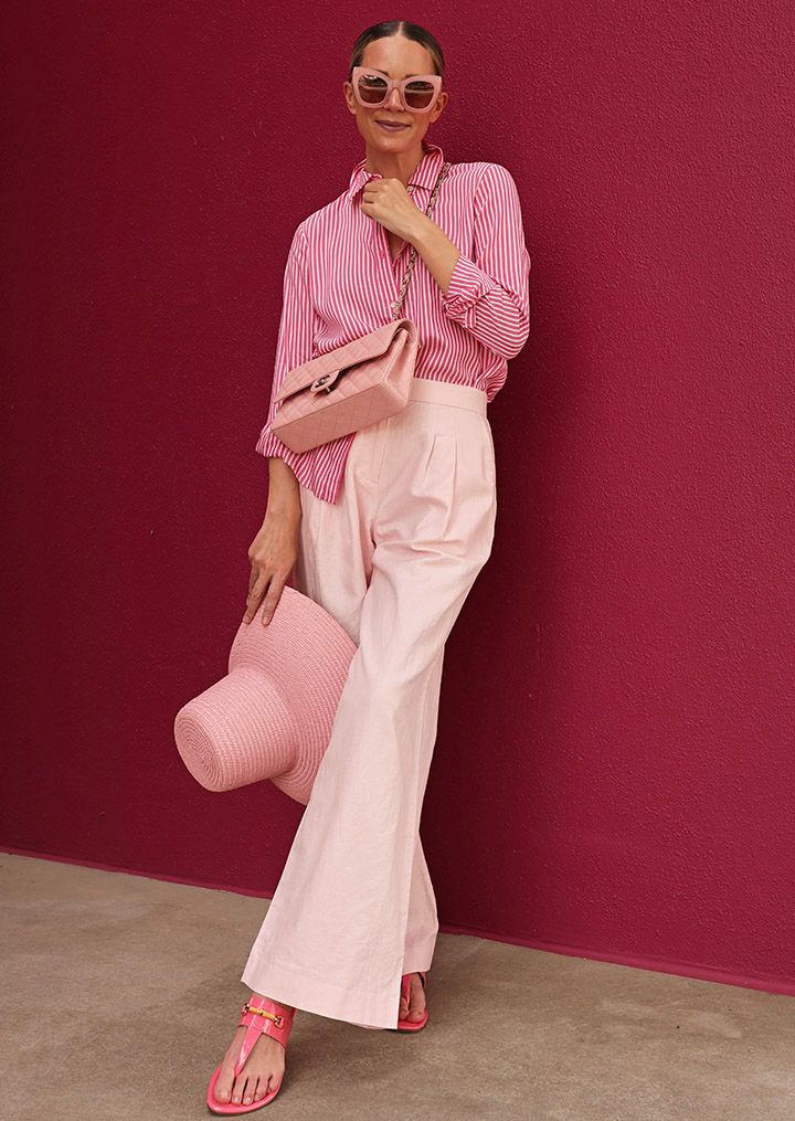 Influencer, Blaire Edie, wearing the pink wide leg trouser, pink slip on sandal with bamboo detail and pink and white stripe button down blouse. 