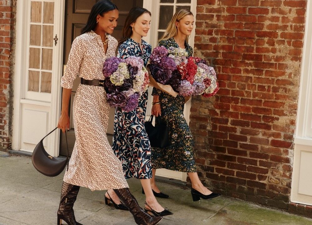 trio of women walking down the city street during the day wearing printed silky midi length dresses