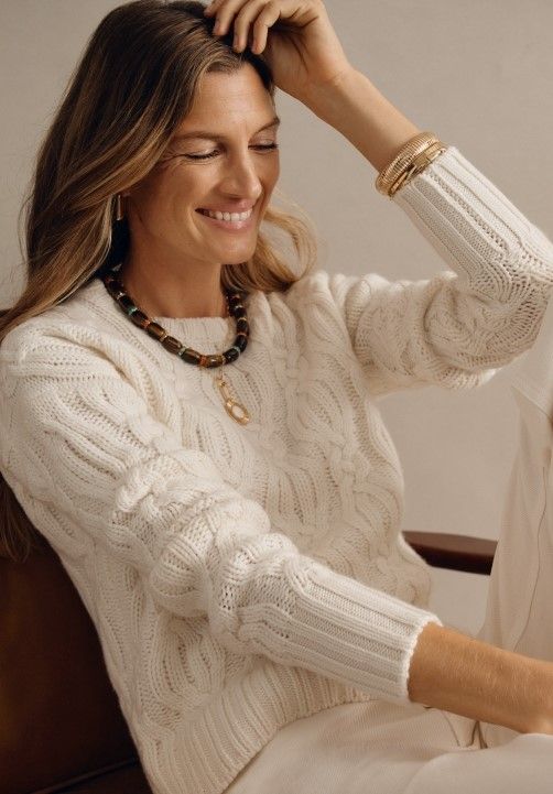 woman seated wearing white crewneck cable chunky sweater